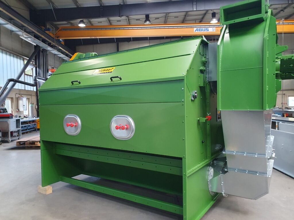 Grüne SIVO UL Reinigungsmaschine von goldsaat Agrartechnik in einer Werkhalle, seitlich mit Metallteilen und Motor ausgestattet.