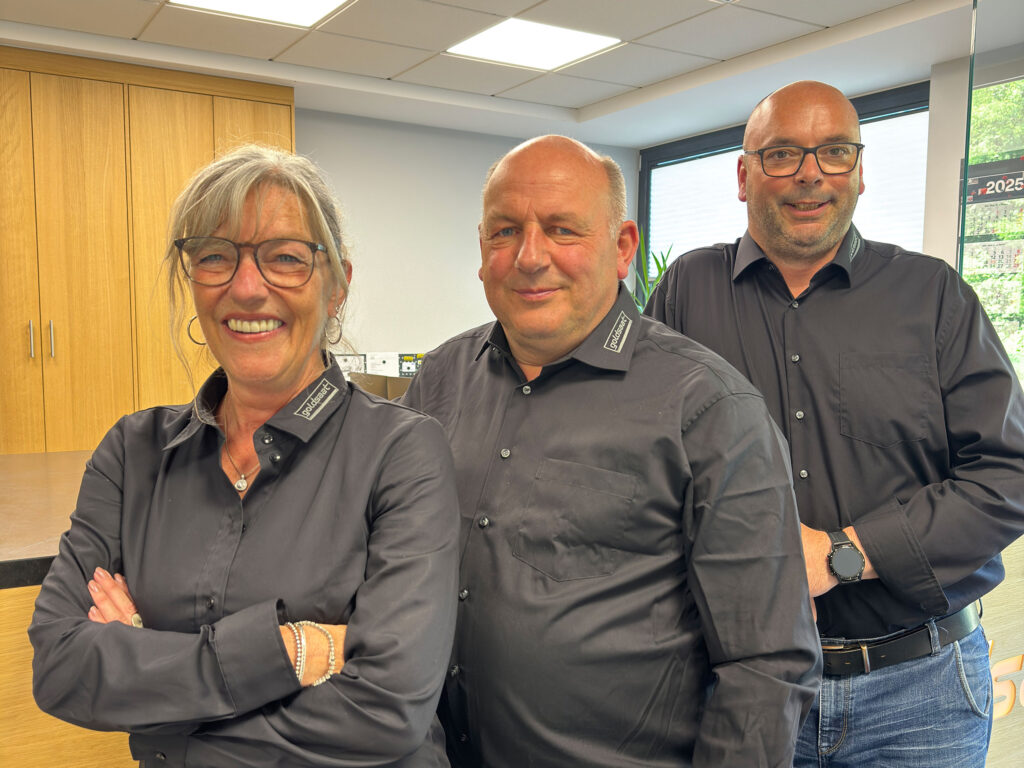 Drei Mitglieder der Geschäftsleitung von Goldsaat Agrartechnik stehen nebeneinander in schwarzer Firmenkleidung und lächeln in die Kamera